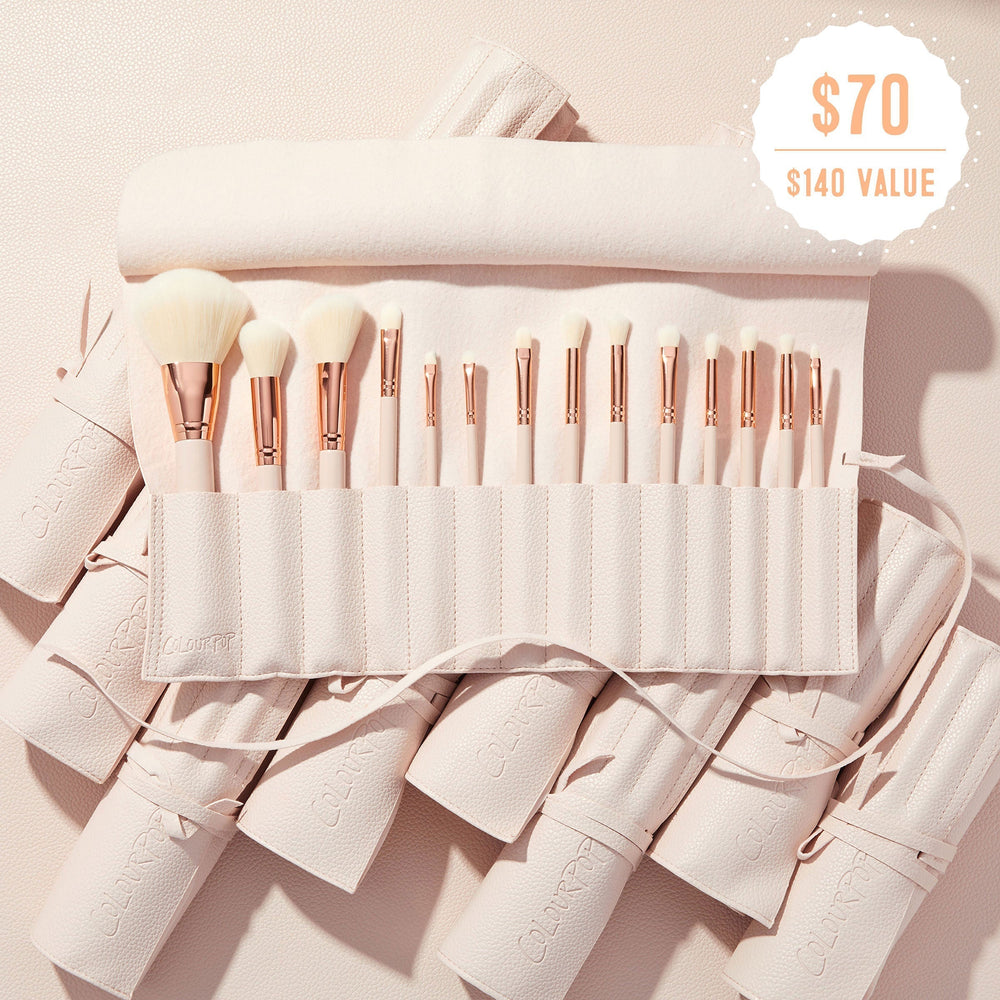 Sweet Fantasy ColourPop Shadow Palette & Brush Set brush roll opens to reveal soft white-bristle face and eye brushes with rose-gold ferrules, arranged in a blush-pink travel case on a textured nude surface, with a $70 ($140 value) badge.
