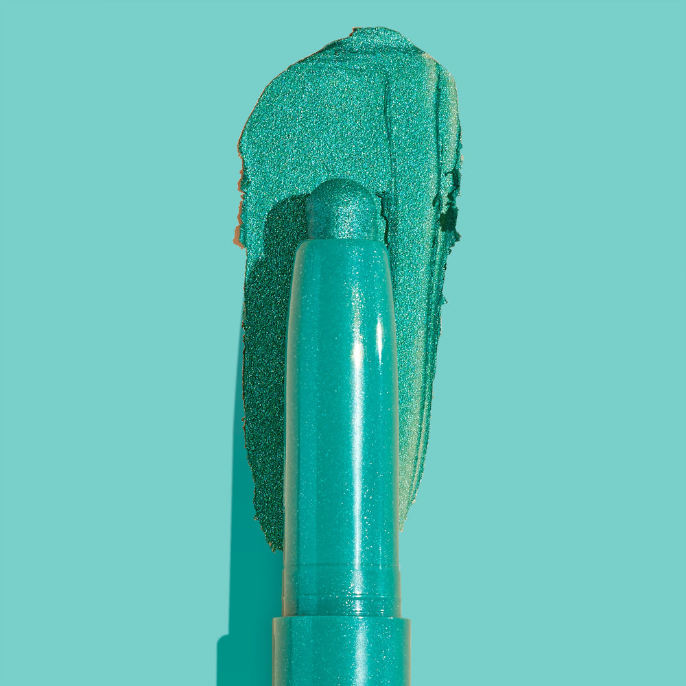 Surf Sesh Shadow Stix swipes a metallic teal eyeshadow swatch behind its creamy twist-up bullet on an aqua backdrop, highlighting shimmer and turquoise payoff; ColourPop Shadow Stix shows smooth, blendable texture.