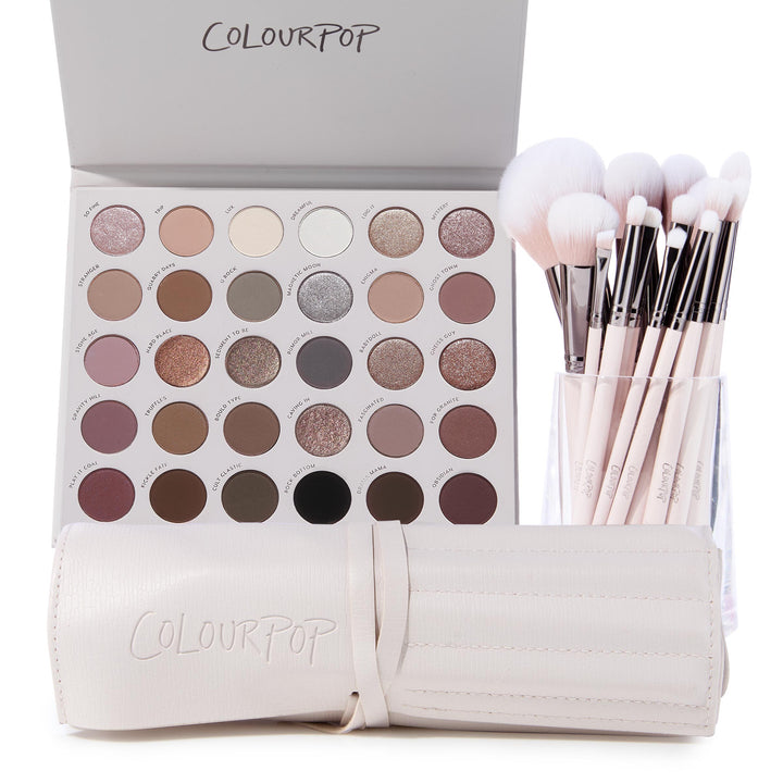 The Ultimate Stunner ColourPop Shadow Palette & Brush Set displaying an open 30‑pan neutral matte and shimmer eyeshadow palette beside pink‑handled makeup brushes in a clear cup and a cream brush roll, on a white background.