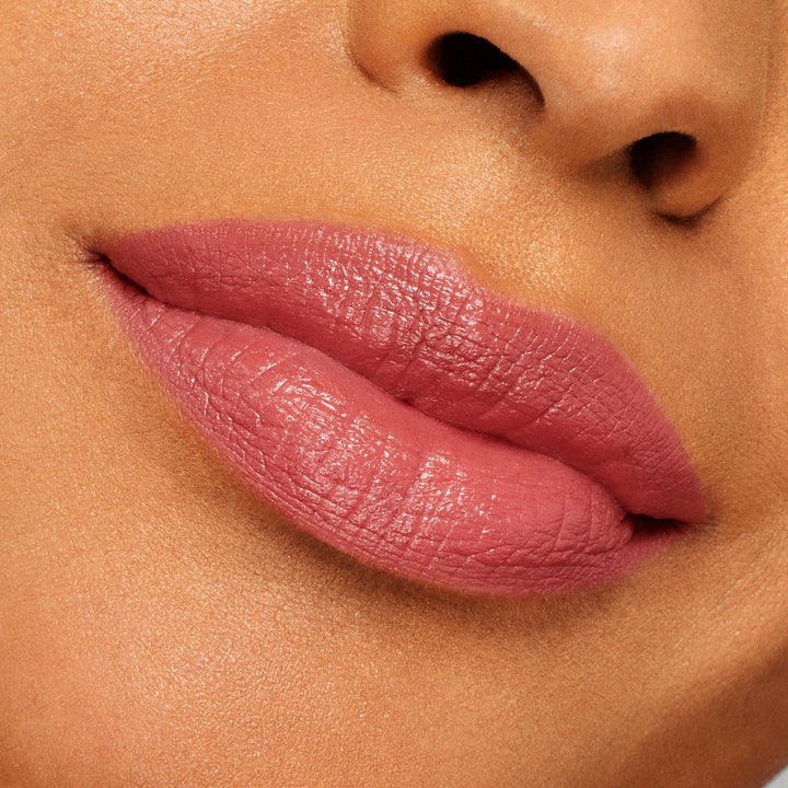 Full lips wearing ColourPop Lippie Stix “It’s Giving,” a rosy mauve pink with a creamy satin sheen, showcasing smooth, even coverage in a close-up swatch against skin for true-to-color shade reference.