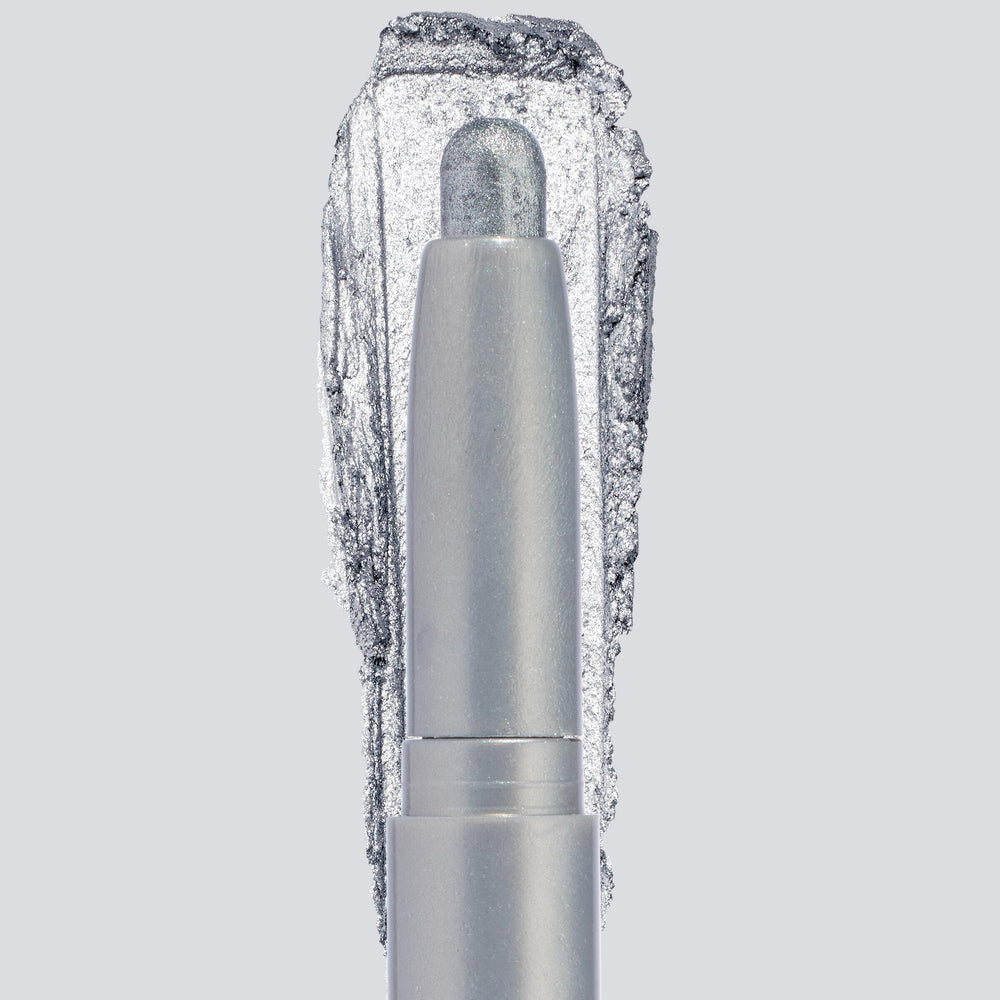 ColourPop Shadow Stix in Witch, Please showcases a creamy icy-silver shimmer, the crayon tip extended with a bold swatch behind to highlight pigment and sparkle, centered in a sleek silver tube on a light gray background.